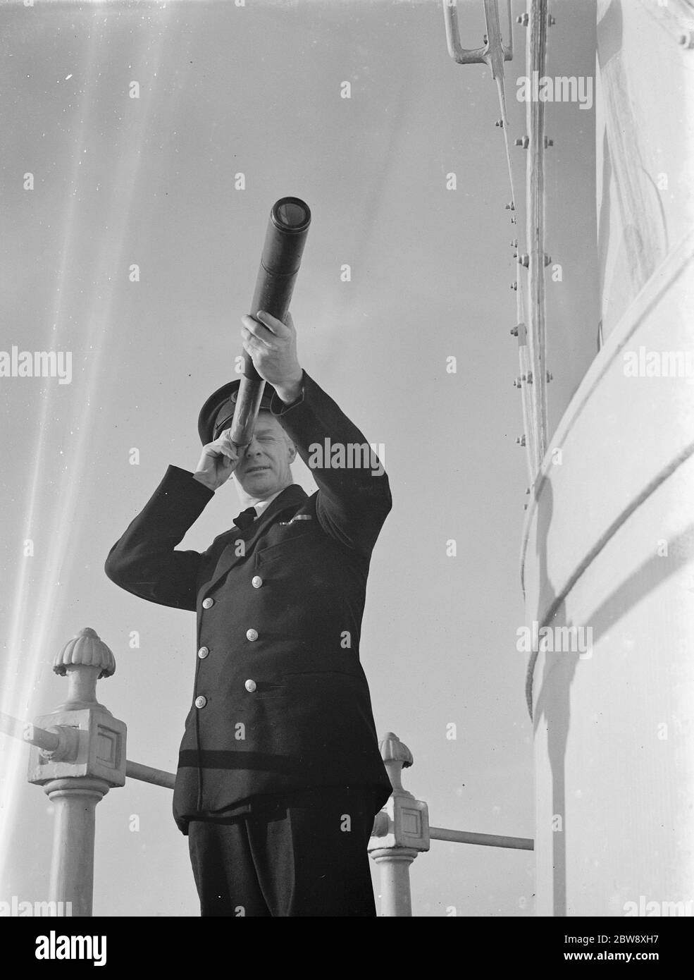 Lighthouse keeper utilizza un telescopio a mano per prendere cuscinetti di navi da luce dal ponte della galleria del faro Dungeness a Kent . 10 febbraio 1939 Foto Stock