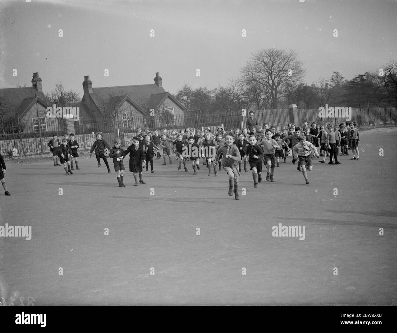 I bambini della scuola si precipitano nel parco giochi della scuola durante il periodo di pausa a Erith , Kent . 1938 . Foto Stock