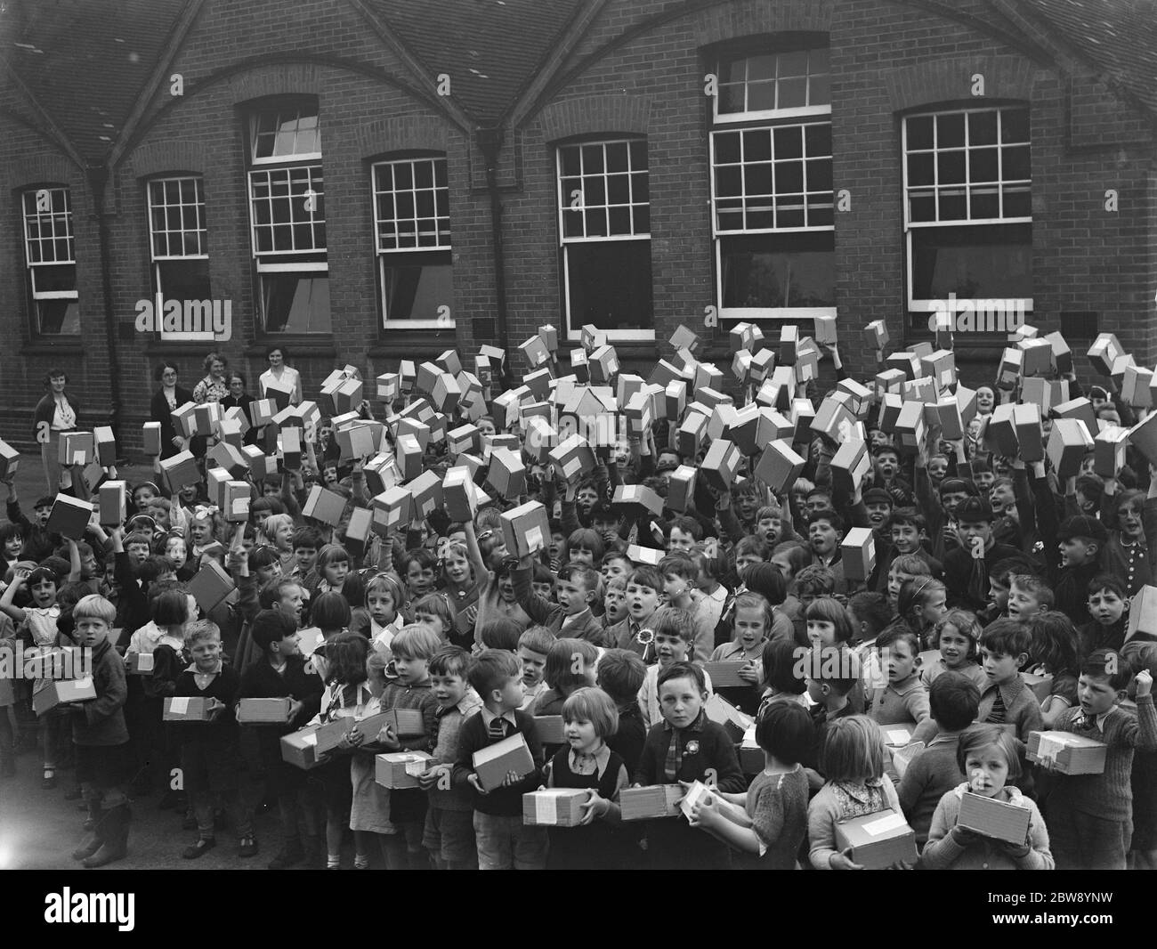 I bambini della scuola di Sidcup Hill School , Kent , fanno ondere le scatole contenenti le loro tazze di incoronazione ricevute per celebrare l'incoronazione del re Giorgio VI . 10 maggio 1937 Foto Stock