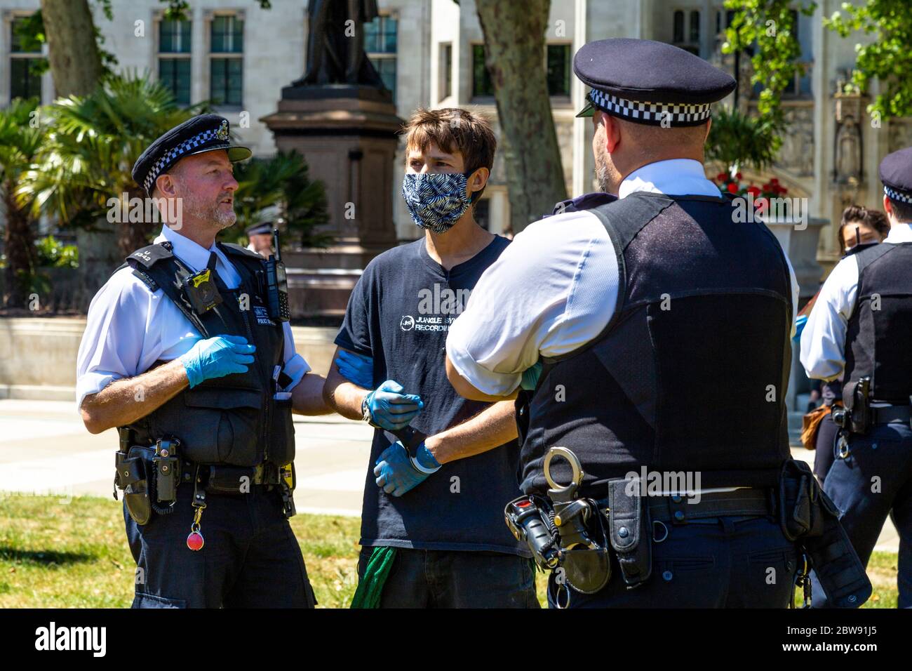 30 maggio 2020 Londra, UK - la ribellione estinguente ha tacito a Westminster la protesta socialmente distanziata contro i cambiamenti climatici, i manifestanti sono stati multati e portati via dalla polizia per aver violato le norme del coronavirus, l'uomo in maschera manomessa, arrestato e tenuto da ufficiali di polizia Foto Stock