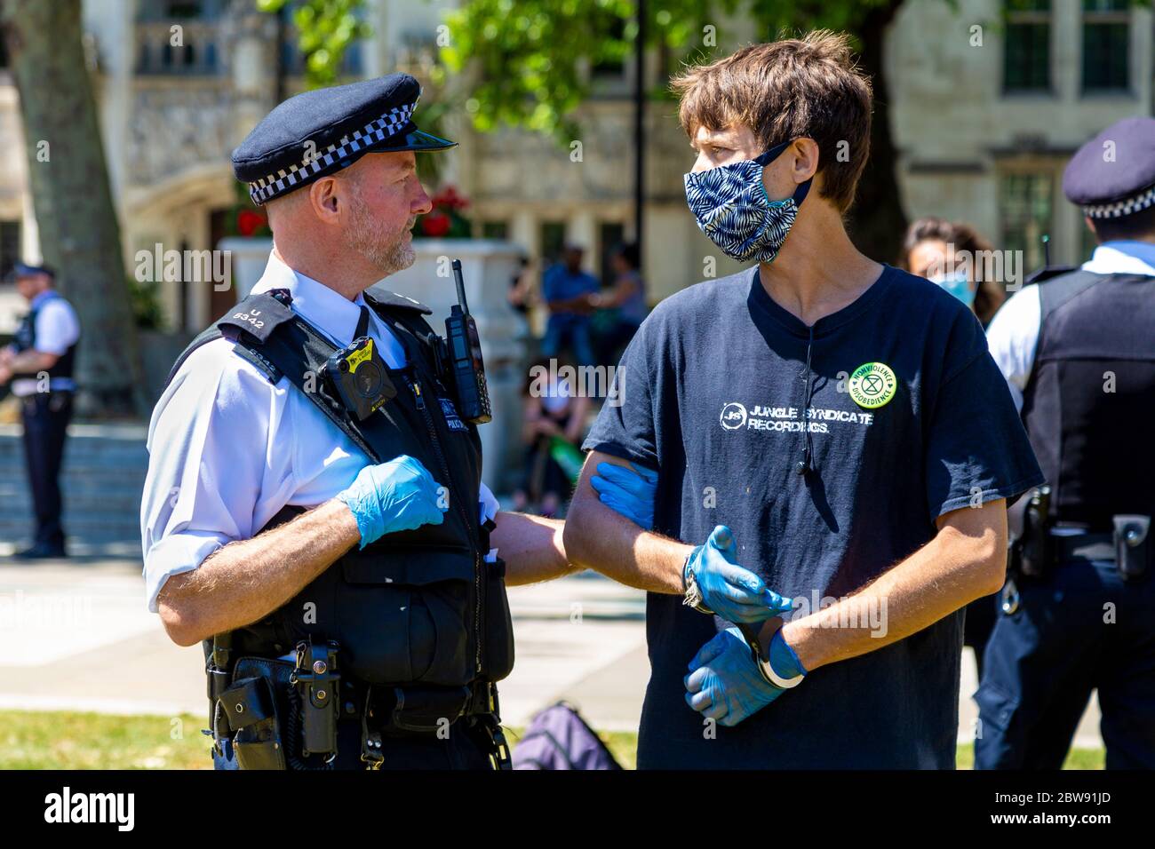 30 maggio 2020 Londra, UK - la ribellione estinguente ha tacito a Westminster la protesta socialmente distanziata contro i cambiamenti climatici, i manifestanti sono stati multati e portati via dalla polizia per aver violato le norme del coronavirus, l'uomo in maschera manomessa, arrestato e tenuto da ufficiali di polizia Foto Stock
