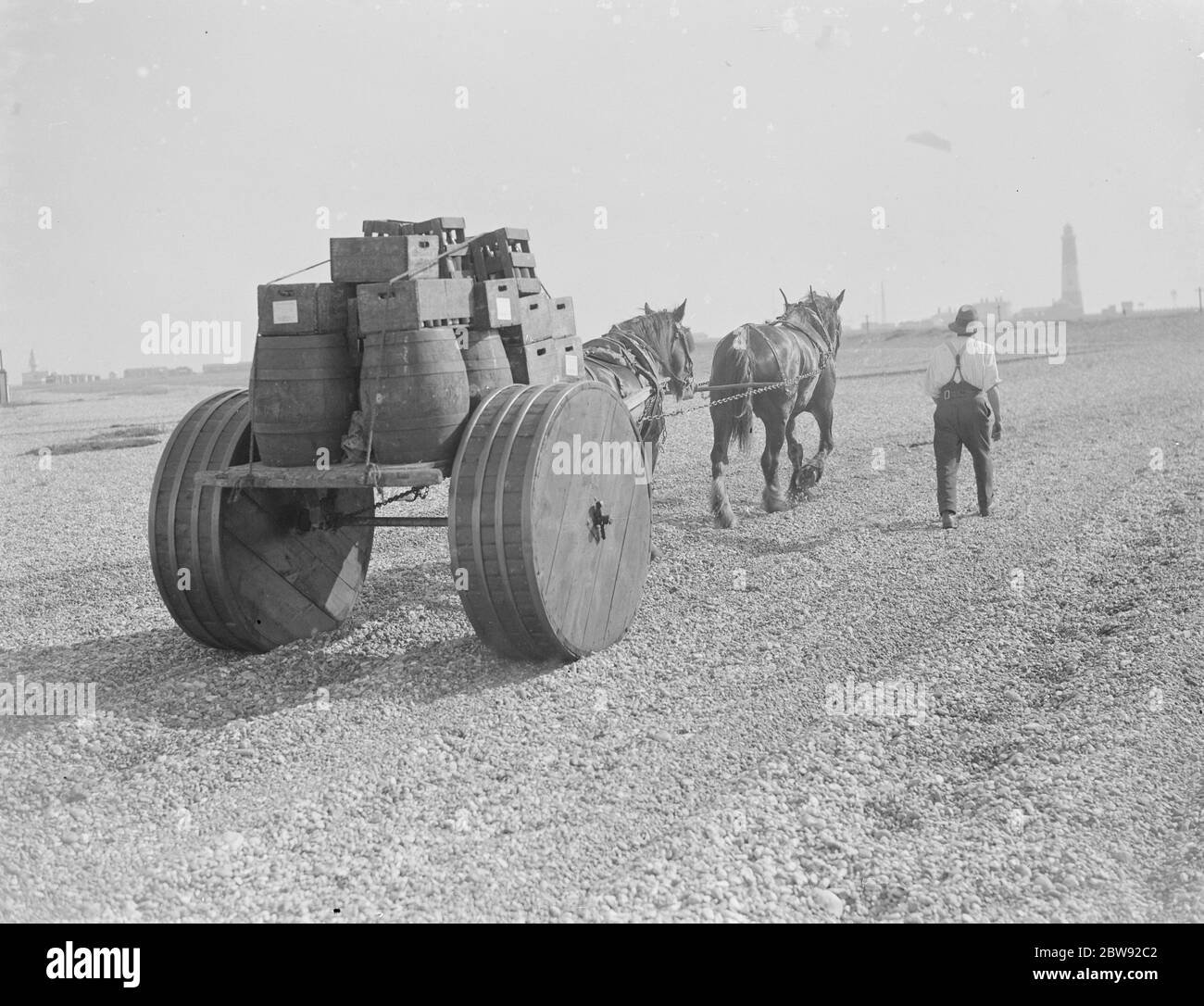 Un uomo con la sua squadra di cavalli che tira barili attraverso la ghiandola a Dungeness in Kent . Il carrello trainato da cavalli ha ruote speciali che lo aiutano a navigare le spiagge senza rimanere bloccato . 1939 Foto Stock