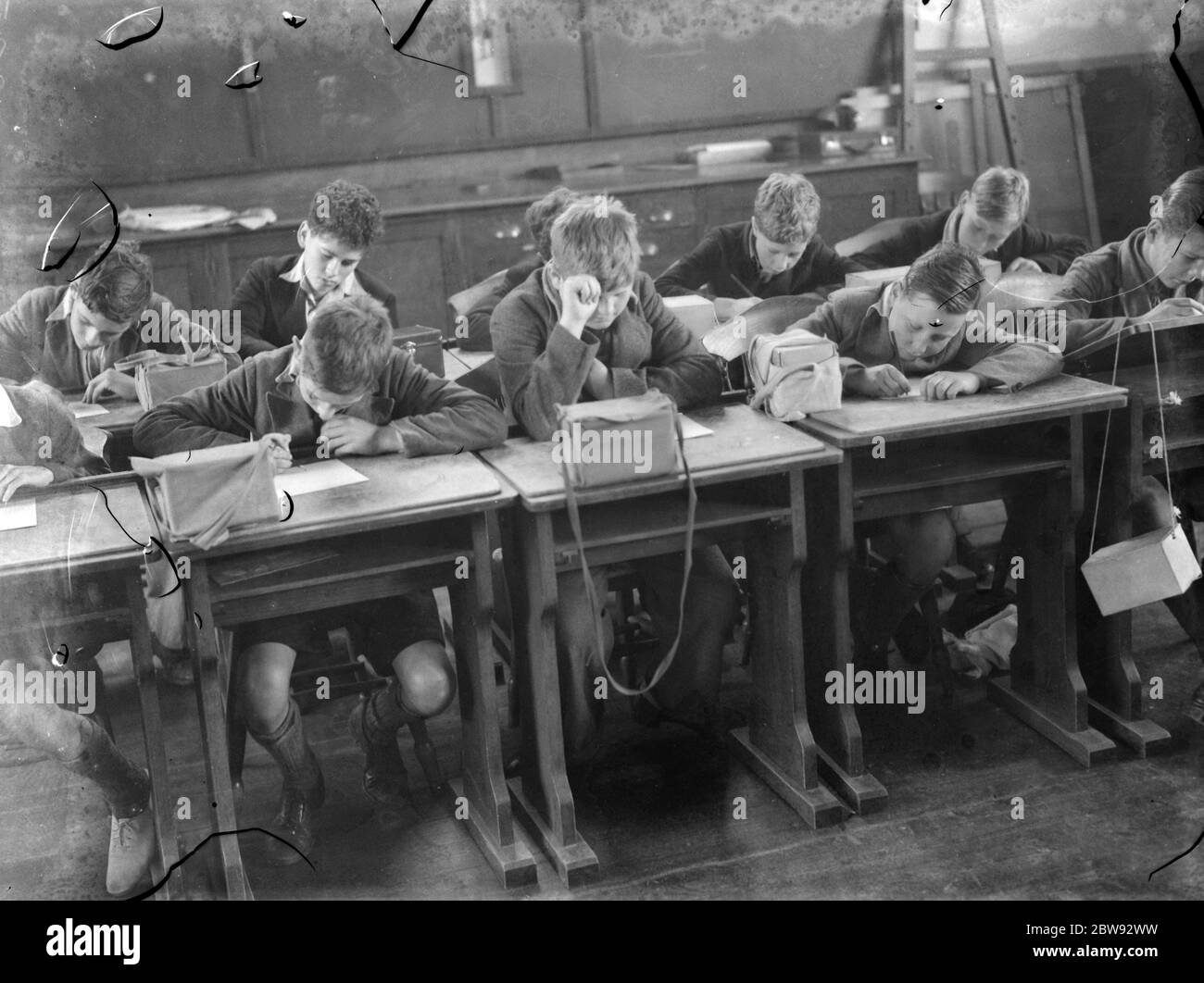 Bambini a scuola a Sidcup , Kent , durante la guerra . Qui sono in una lezione con le loro maschere a gas vicino a portata di mano in caso di bombardamento . 1939 Foto Stock