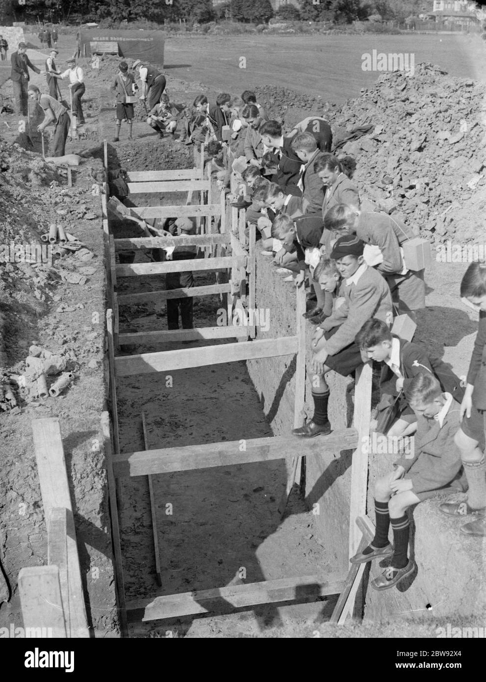 Bambini a scuola a Sidcup , Kent , durante la guerra . Qui stanno guardando i lavoratori che scavano una trincea per un riparo A R P . 1939 Foto Stock