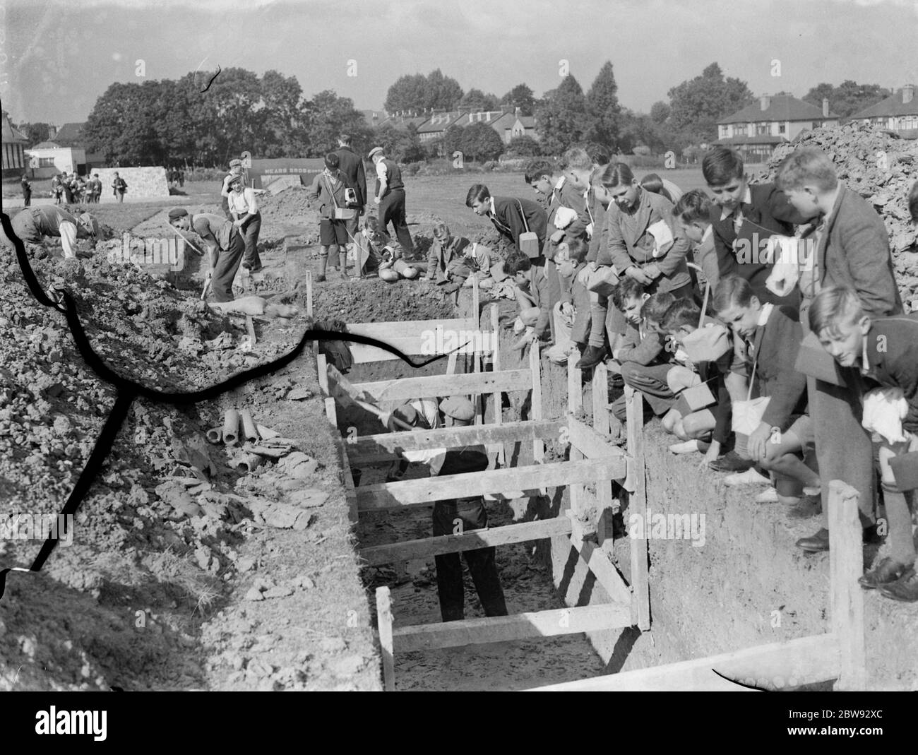Bambini a scuola a Sidcup , Kent , durante la guerra . Qui stanno guardando i lavoratori che scavano una trincea per un riparo A R P . 1939 Foto Stock