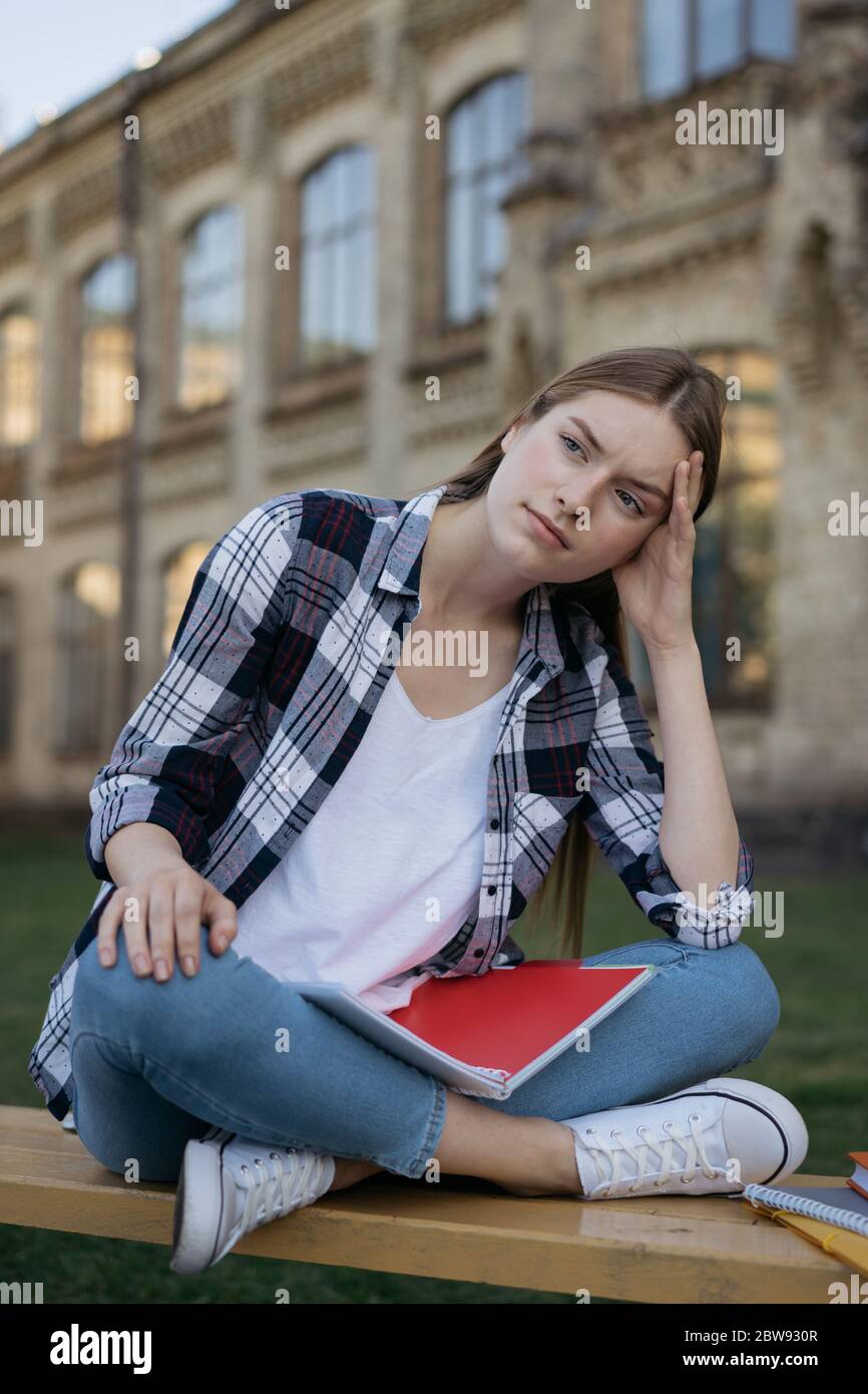 Studente deluso dai risultati degli esami. Ritratto di donna infelice con viso stanco e triste seduta su panchina, lei perde speranza. Concetto di errore degli esami Foto Stock