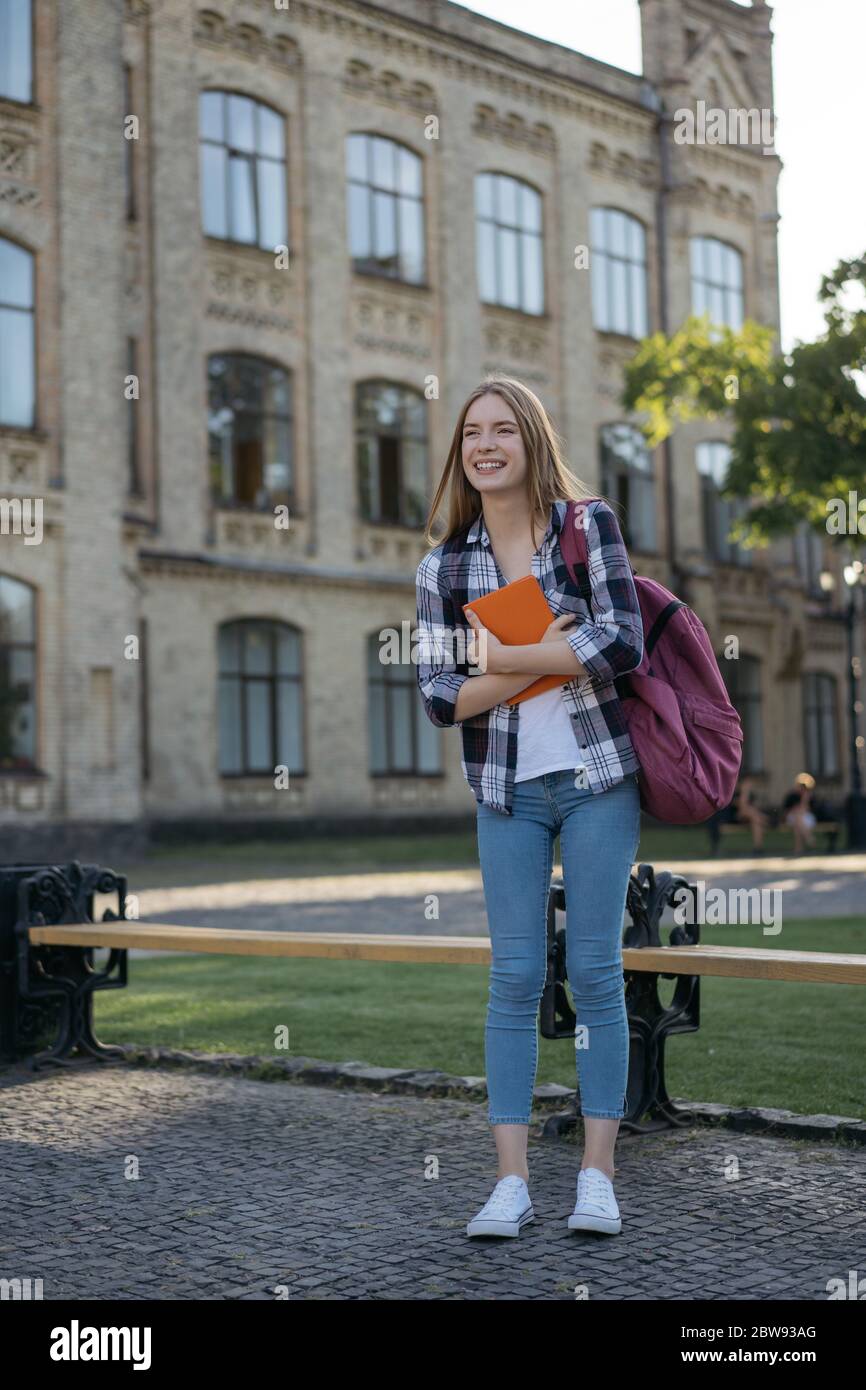 Felice studente universitario a piedi per l'università. Concetto di istruzione. Ritratto di bella donna con zaino e libri in piedi nel parco Foto Stock