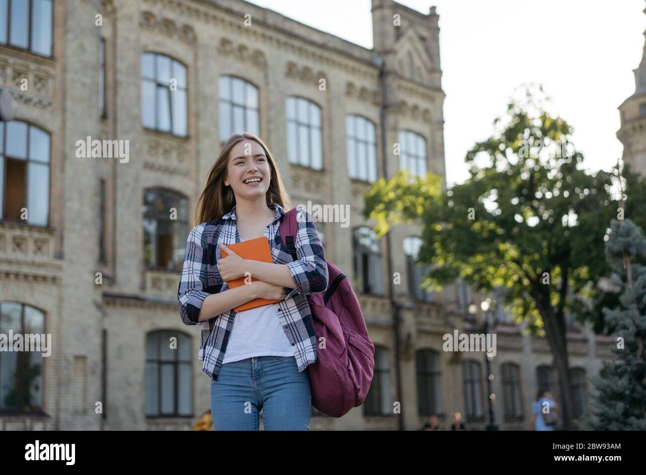 Studente con zaino e libri a piedi per l'università. Concetto di istruzione. Ritratto di felice bella donna in piedi nel parco Foto Stock