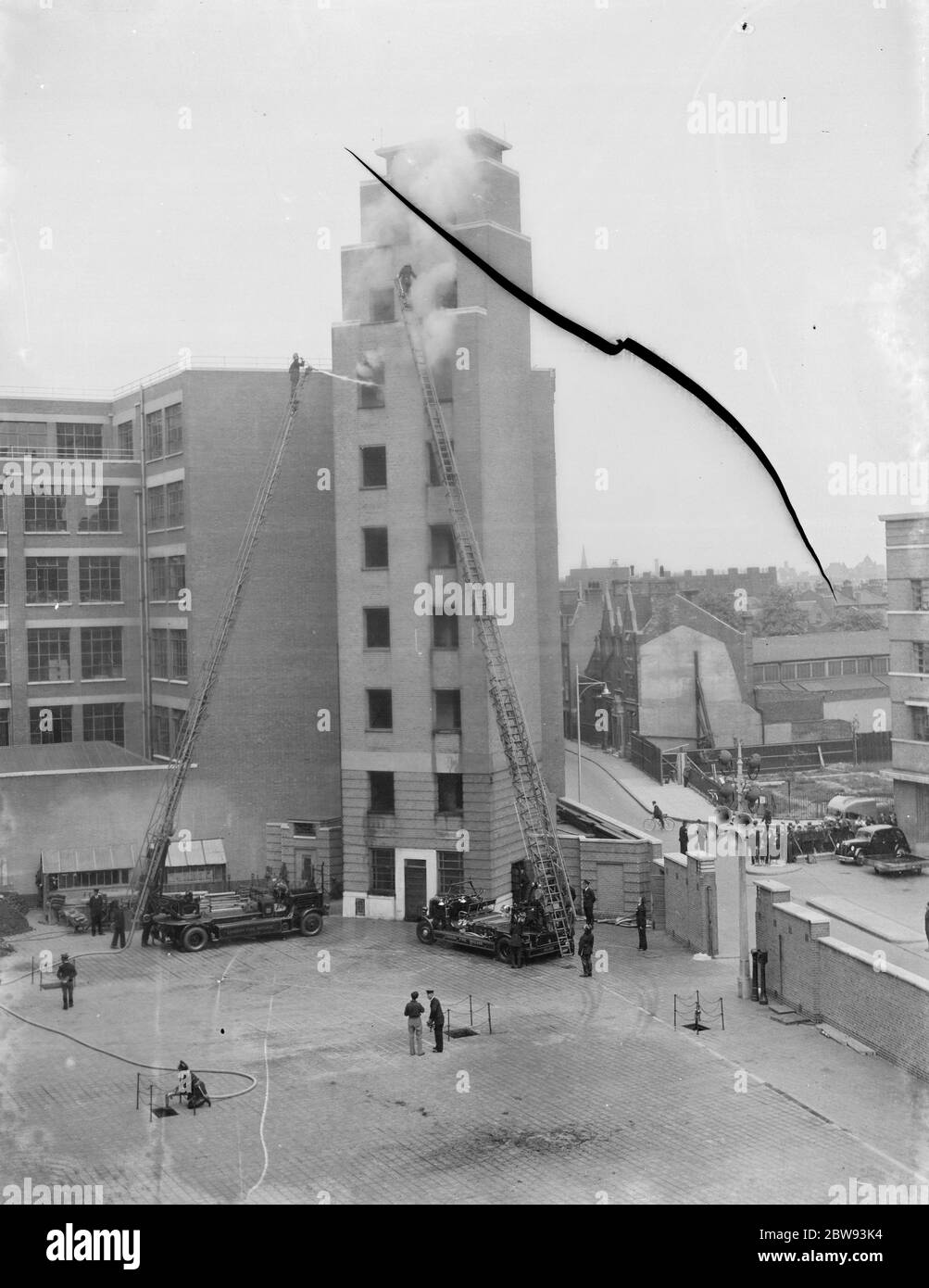 Una mostra di London Fire Brigade a Lambeth , Londra. I vigili del fuoco usano scale di prolunga per accedere e per tubi le finestre del pavimento superiore di un edificio alto durante la dimostrazione . 1939 Foto Stock