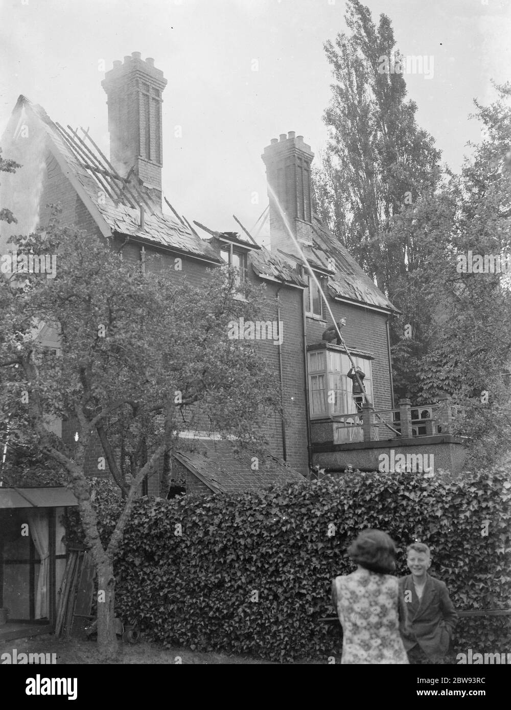 I vigili del fuoco rispondono ad un incendio di casa a Chislehurst , Kent . Tubo di acqua di vigile del fuoco nella finestra superiore dell'edificio. 1939 Foto Stock