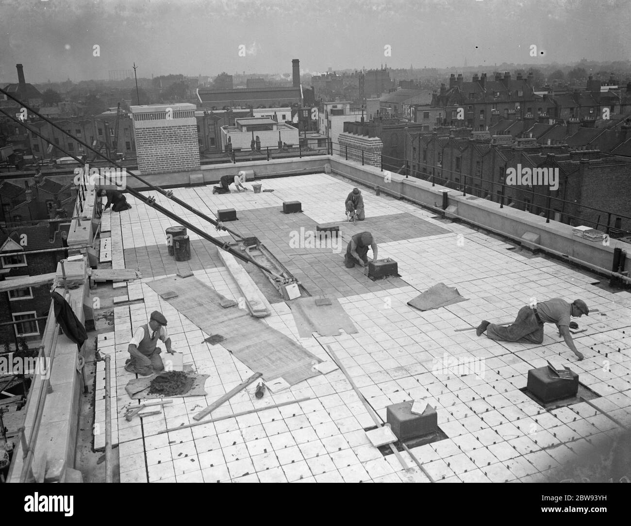 Lavoratori della Val De Travers Asphalt Limited , una società di pavimentazione , che lavorano alla pavimentazione del tetto del London Jewish Hospital di Steppey Green . 1938 Foto Stock