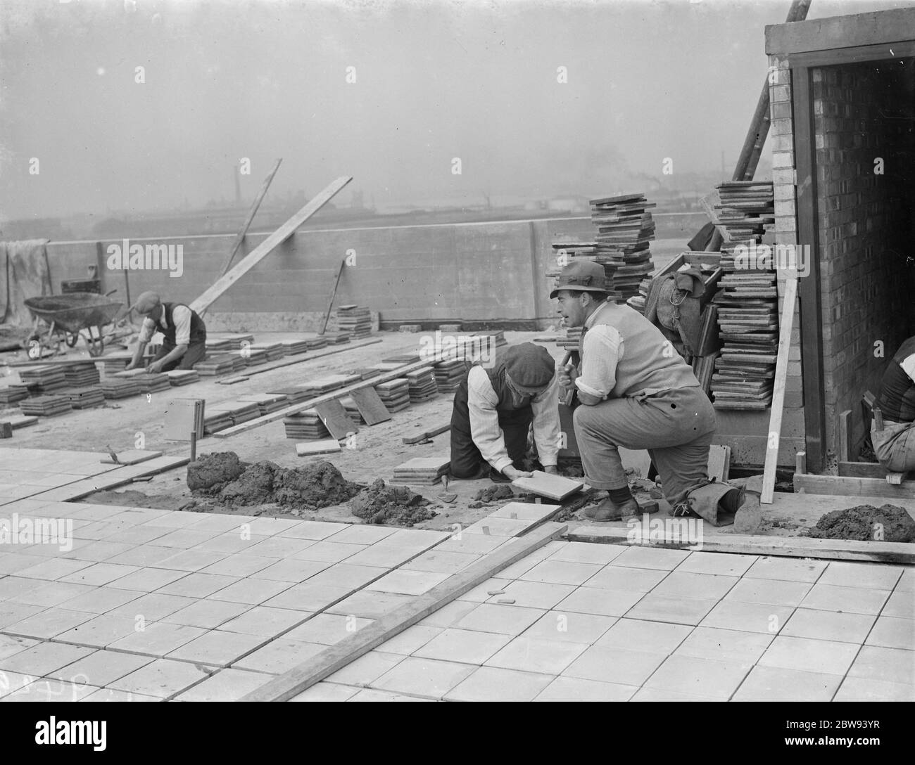 Lavoratori della Val De Travers Asphalt Limited , una società di pavimentazione , che lavora su un tetto a Greenwich , Londra . 1938 Foto Stock