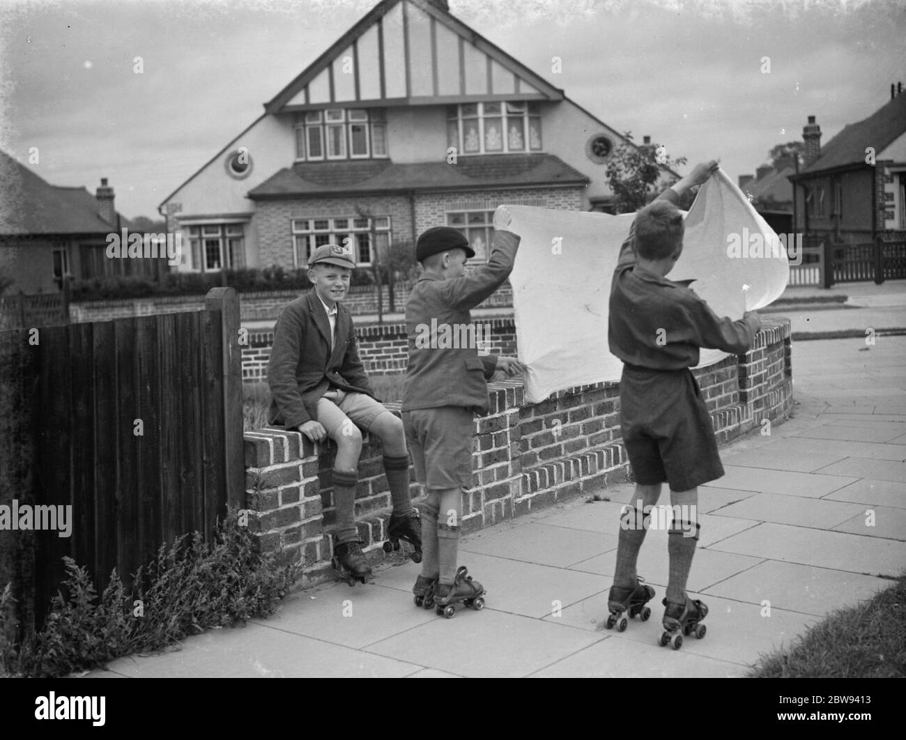 I ragazzi pattinano a rulli usando una lastra come vela a vento . 1938 Foto Stock
