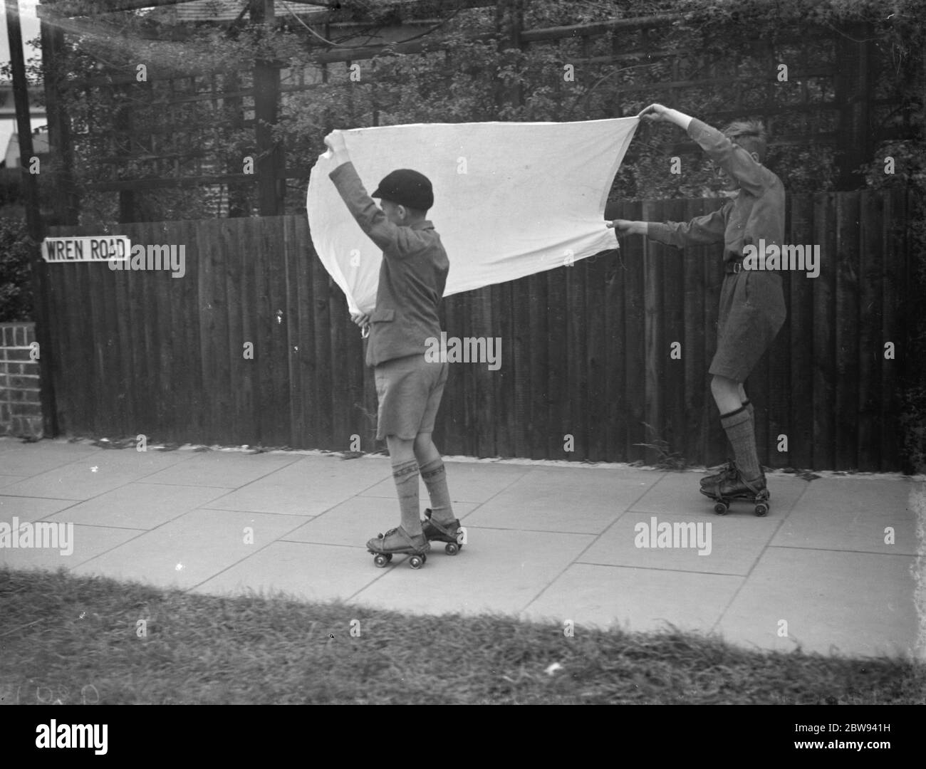 I ragazzi pattinano a rulli usando una lastra come vela a vento . 1938 Foto Stock
