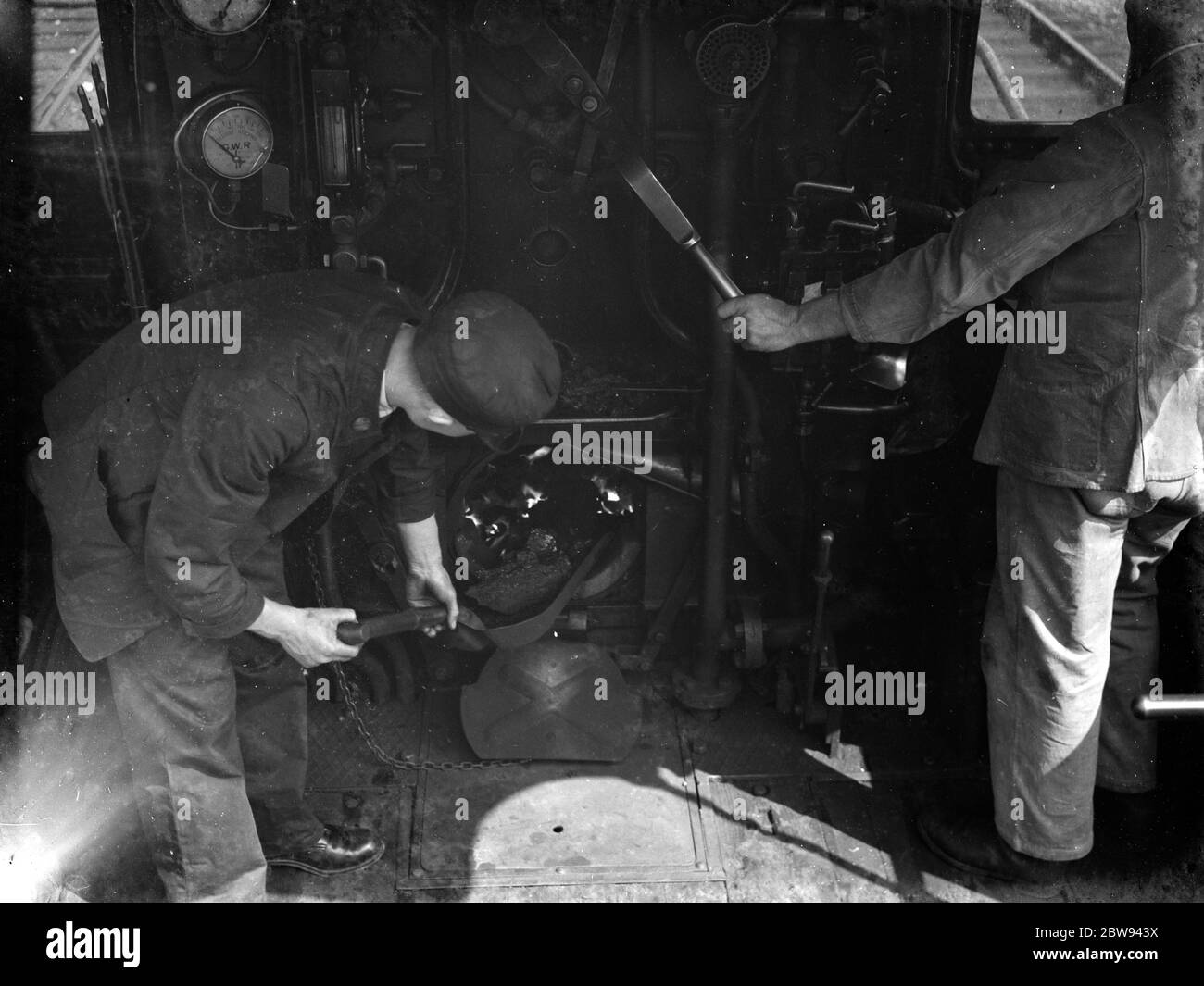 All'interno di una cabina di un motore ferroviario . I vigili del fuoco scuotono il carbone nel fuoco . 1938 Foto Stock