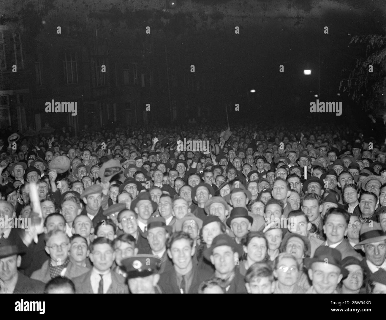 Una folla si riunisce per guardare il Palazzo di Cristallo bruciare in lontananza . 1936 Foto Stock