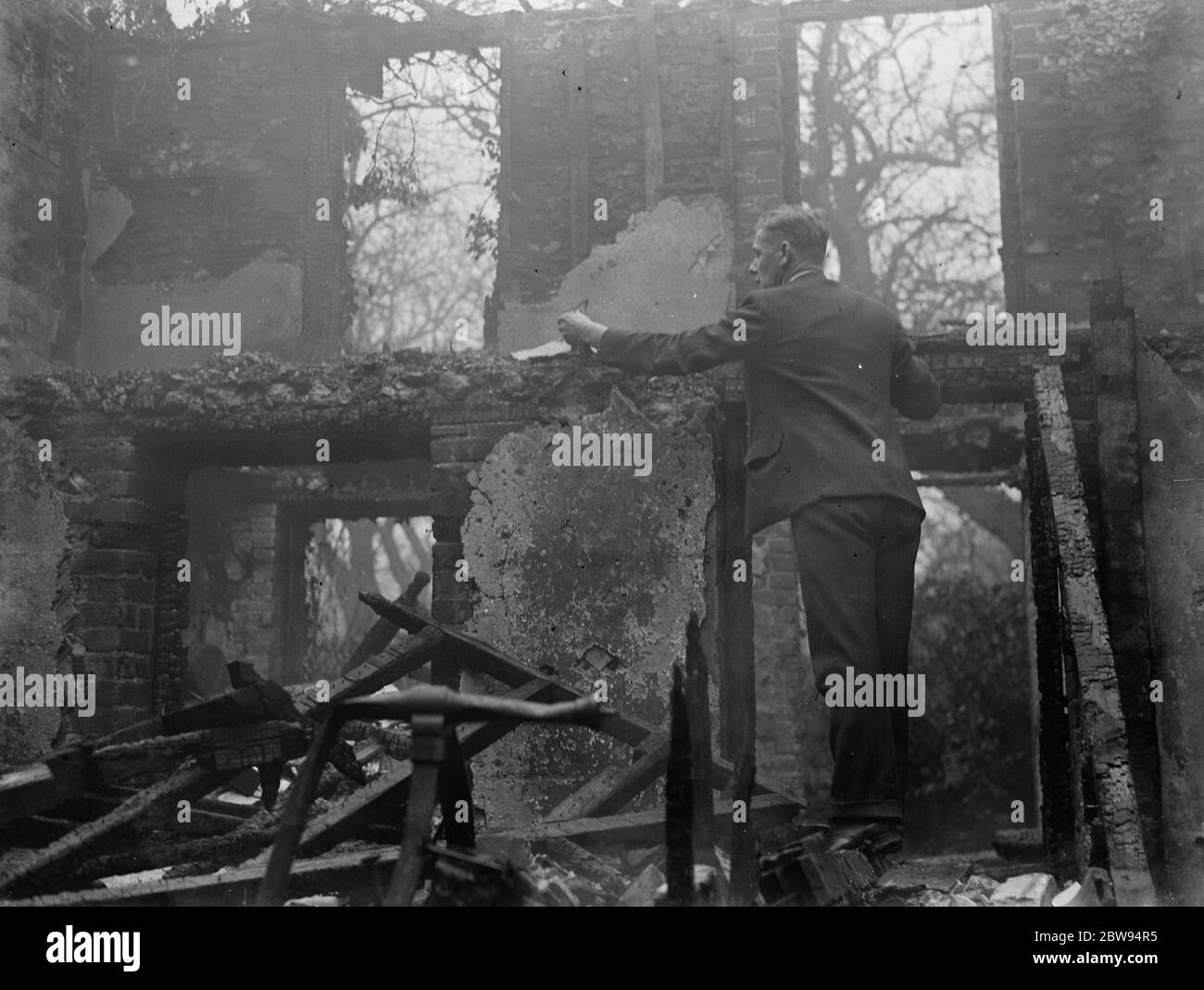Un uomo esamina ciò che è lasciato dietro a seguito di un incendio in un cottage a Chelsfield , Kent . 1936 Foto Stock