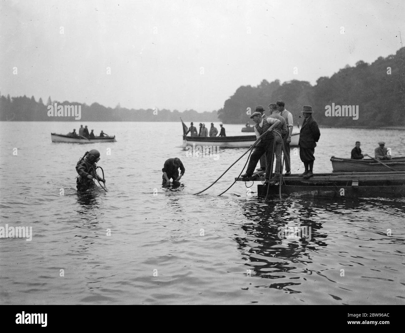 Prove record di velocità rimandate di nuovo quando Miss Inghilterra III fouls scivola . Kaye Don ha sostenuto un altro colpo di sfortuna nel suo tentativo di riconquistare il record mondiale di velocità dell'acqua per la Gran Bretagna in Miss Inghilterra III , Lord Wakefield ' s £ 40 , 000 velocità barca , a Loch Lomond , Scozia , quando lo scivolo che porta al bordo dell' acqua crollò e si strinse un buco nello scafo della barca . I subacquei dell'Ammiralty hanno lavorato tutta la notte per sostituire lo scivolo e fare un esame subacqueo del lavoro . Operai che portano una nuova rotaia giù alla riva per sostituire quella rotta mentre un subacqueo si alza vicino pronto per arrivare a. Foto Stock