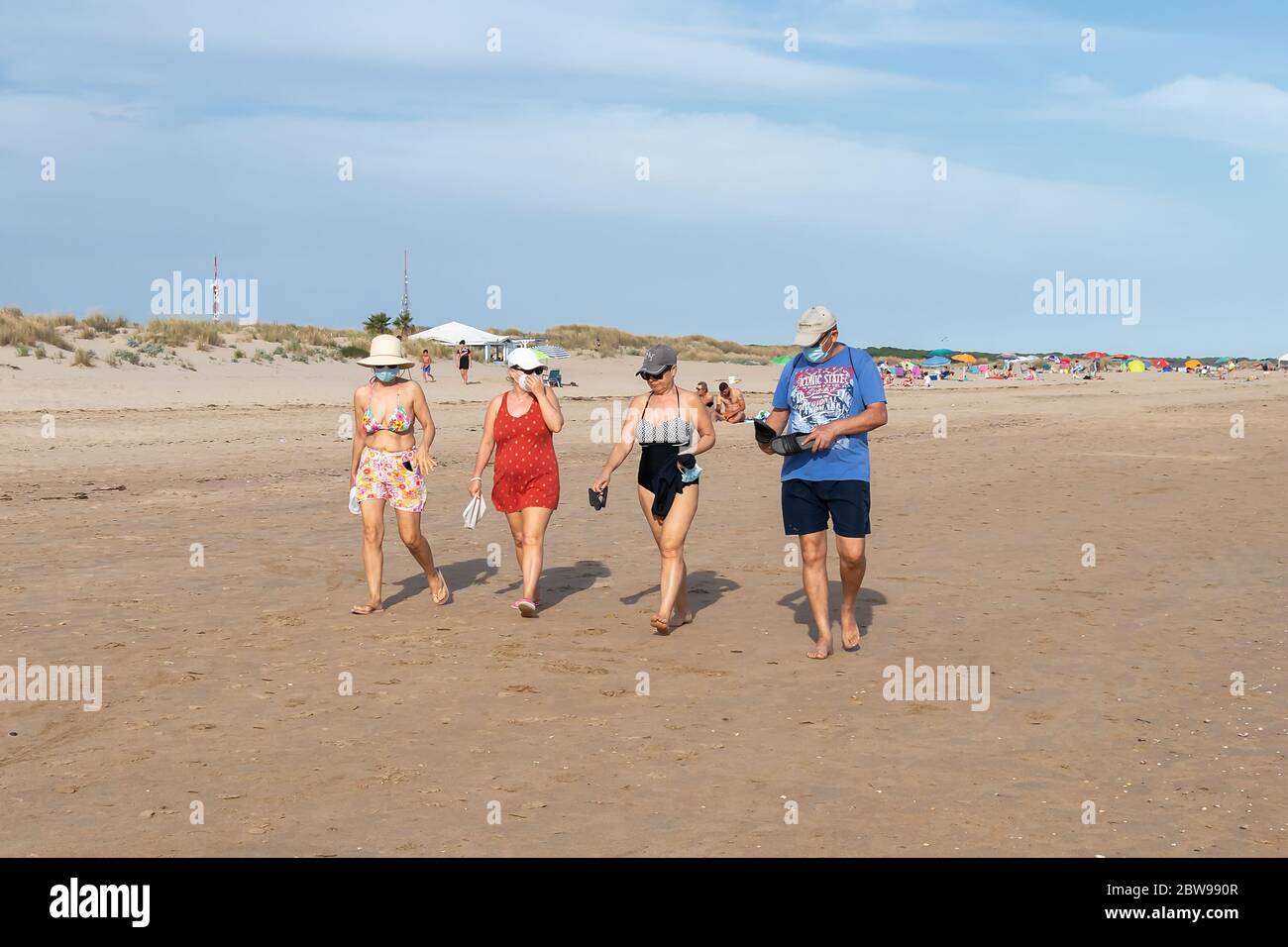 Punta Umbria, Huelva, Spagna - 30 maggio 2020: Persone che camminano vicino alla spiaggia indossando maschere protettive o mediche durante lo stato di allarme e la quarantena Foto Stock