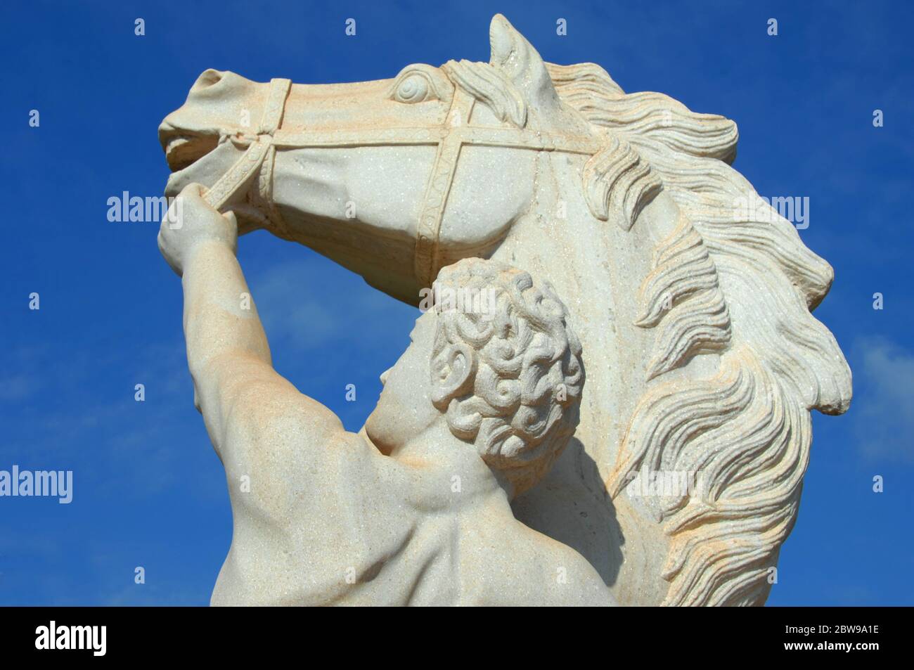 Bella statua raffigurante l'uomo che tiene il cavallo accanto alla briglia. La statua è sull'isola di Kauai, Hawaii e fa parte del paesaggio in uno dei resor Foto Stock