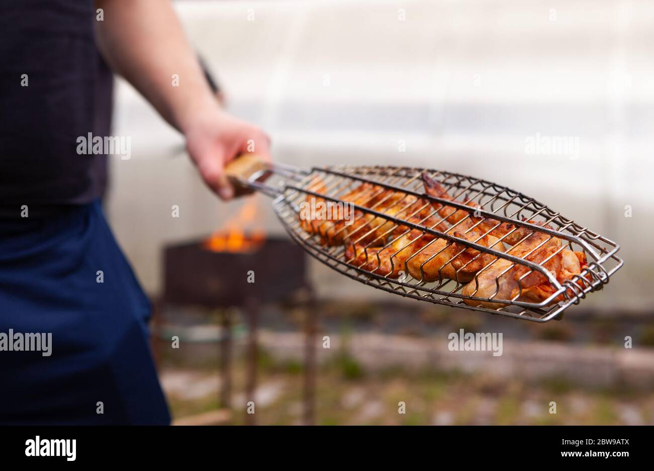 Uomo che cucina carne al barbecue. Divertimento estivo. Foto Stock
