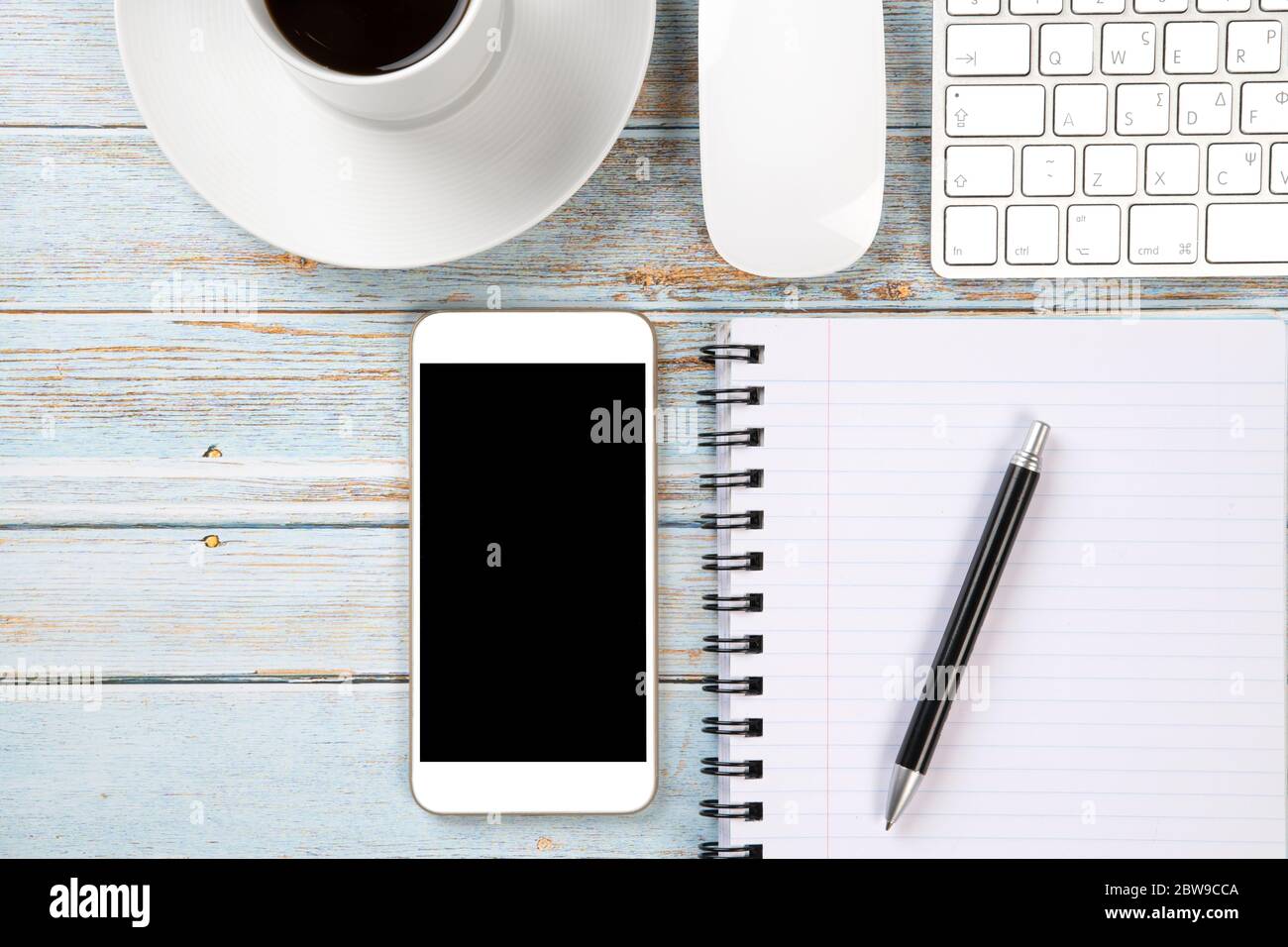 Scrivania in legno con vista dall'alto, mobile, tastiera, mouse, una tazza di caffè e un notebook, pronta per il lavoro Foto Stock