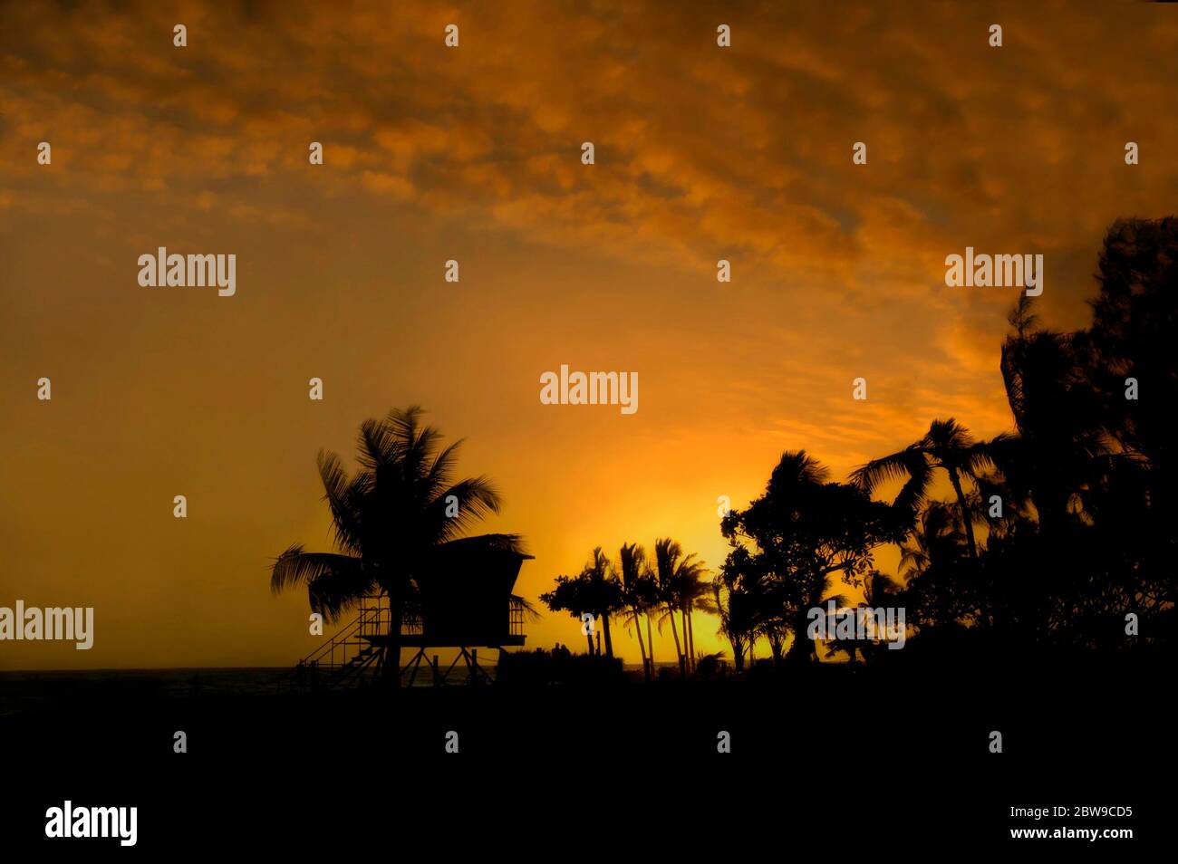 Il salvagente è silhouette dal sole che tramonta sull'isola di Kauai, Hawaii. Glorioso mix di oro e arancio per una bella fine della giornata. Foto Stock