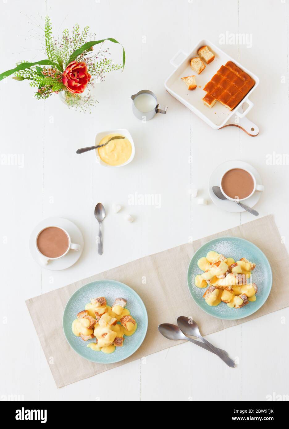 Panini con zabaglione o crema alla vaniglia, o eggnog, gustoso dessert o portata principale. Sfondo bianco tavolo di legno. Foto Stock