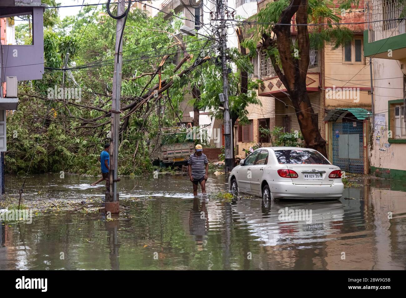 Strada urbana allagata con veicoli, pedoni e alberi sradicati dopo la grave tempesta ciclonica 'Amphan' sciopero al Bengala Occidentale, India Foto Stock