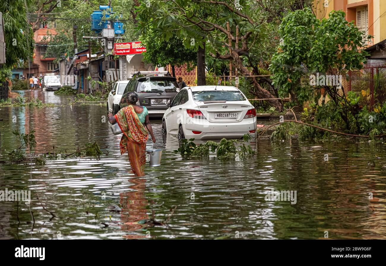 Strada urbana allagata con veicoli, pedoni e alberi sradicati dopo la grave tempesta ciclonica 'Amphan' sciopero al Bengala Occidentale, India Foto Stock