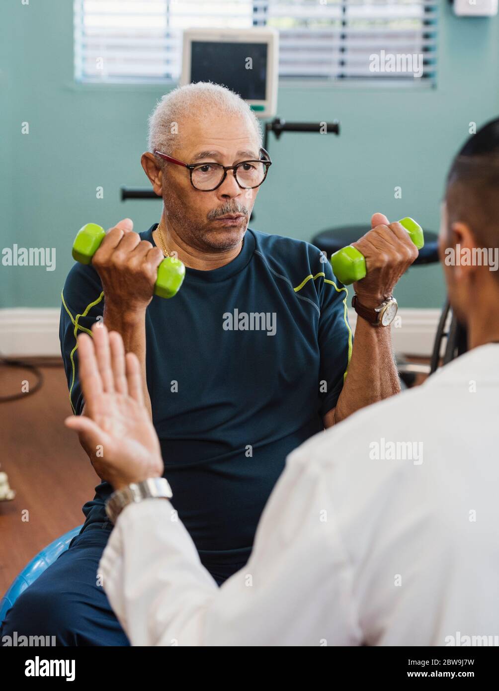 Uomo anziano che si esercita con il terapeuta durante la terapia fisica Foto Stock