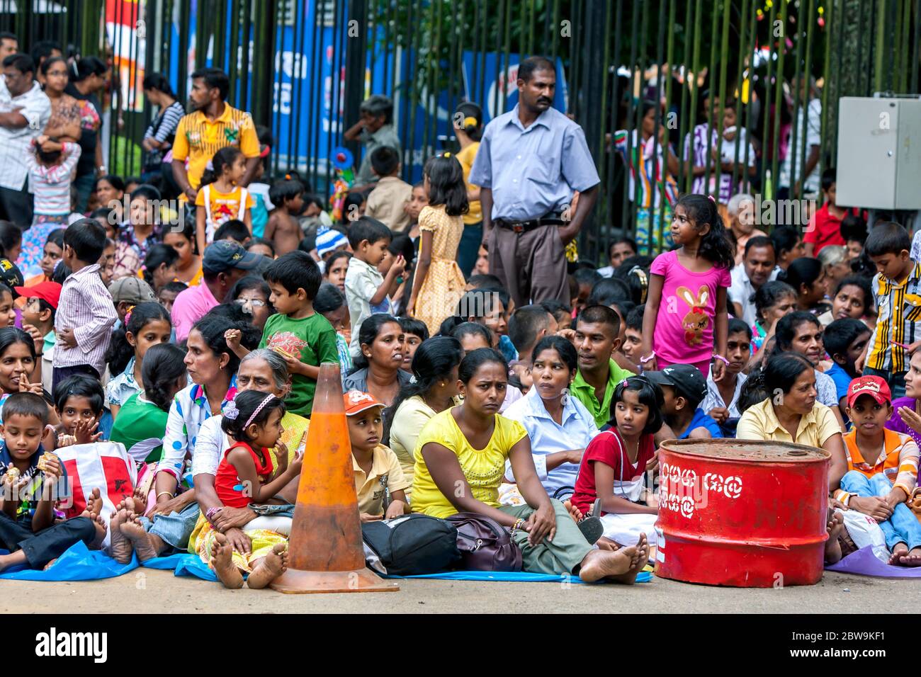 Una folla enorme di persone si siedono lungo una strada a Kandy in Sri Lanka prima dell'inizio del buddista Esala Perahera (grande processione). Foto Stock