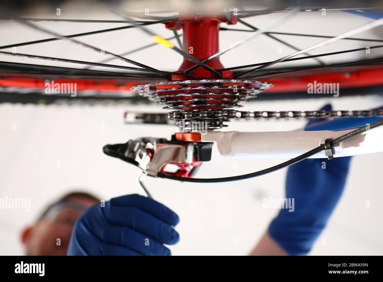 Uomo con guanti che ripara la ruota di bicicletta con chiave del vano Foto Stock