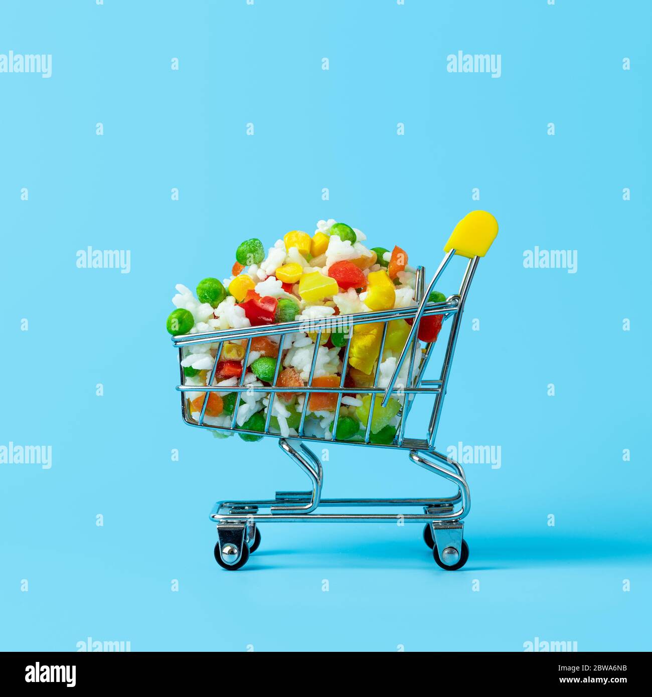 Verdure surgelate assortite nel carrello giocattolo su sfondo blu. Pieno di carrelli assortiti per negozi di prodotti alimentari e verdure surgelate. Ritaglio quadrato Foto Stock