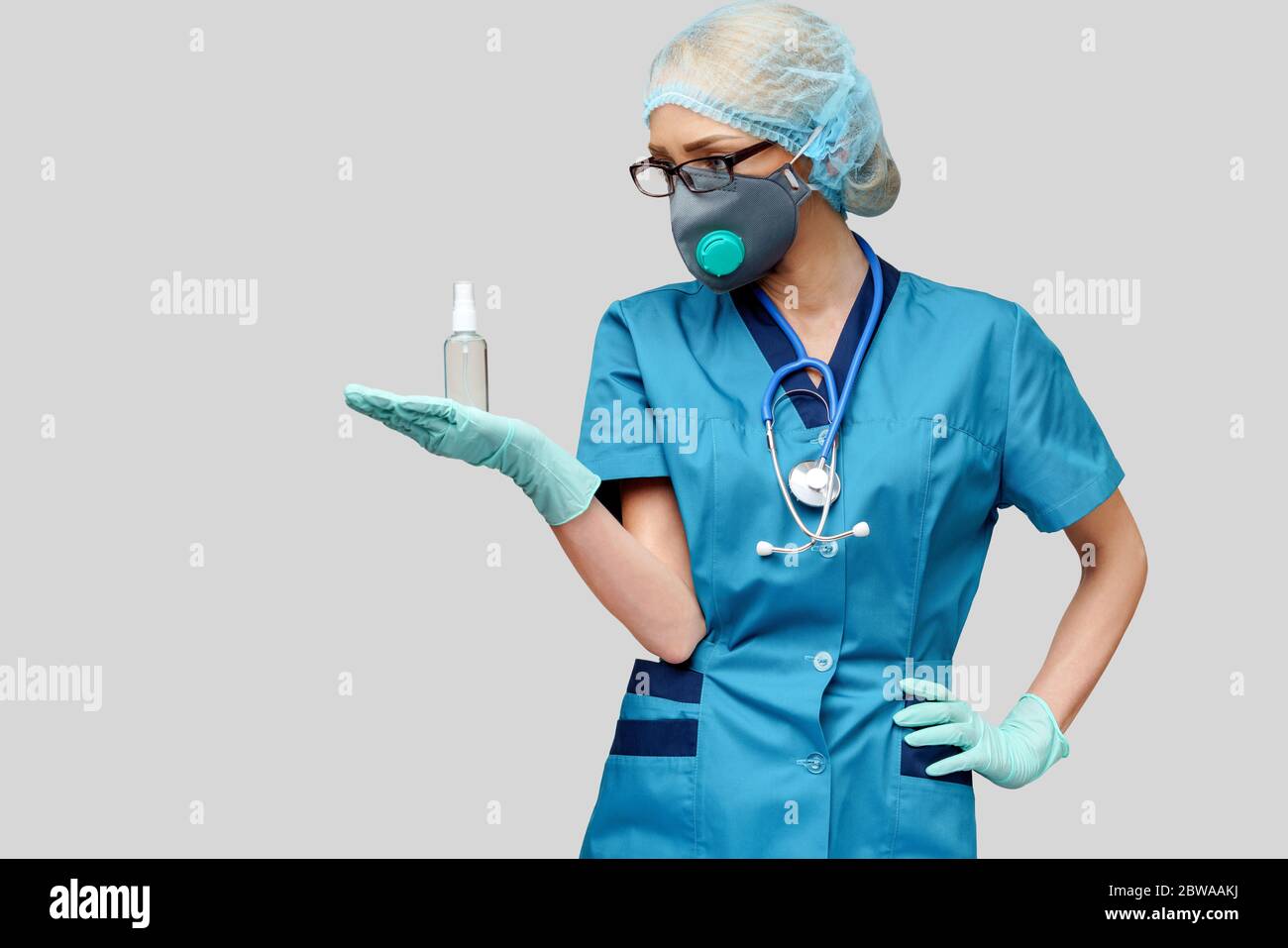 medico medico infermiere che indossa la maschera protettiva - contenente il flacone di spray o gel igienizzante Foto Stock