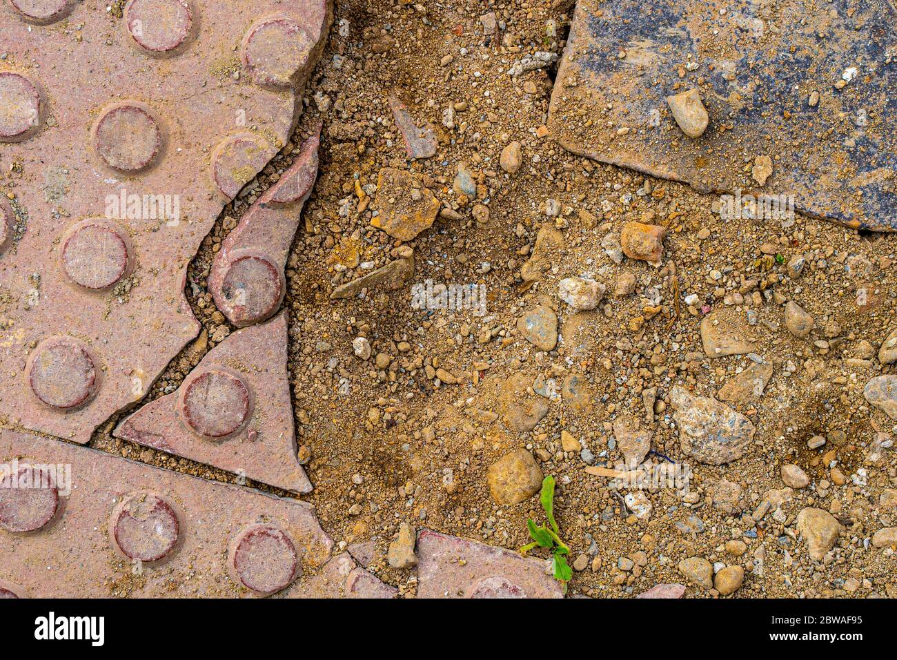 Marciapiede in costruzione. Struttura di pavimentazione tattile rotta con terreno. Foto Stock