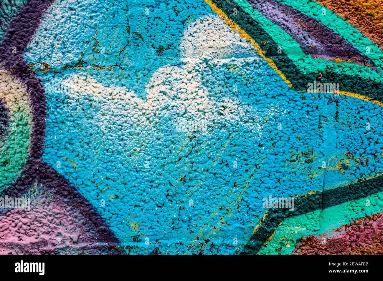 Primo piano su graffiti geometrici sulla struttura della parete in blocchi di cemento. Street art background. Azzurro, multicolore. Foto Stock