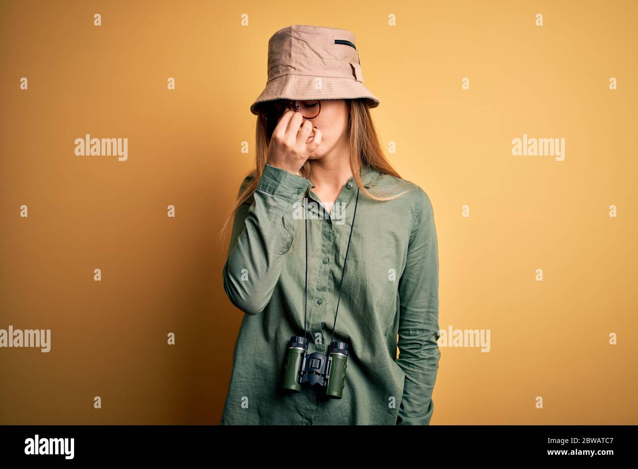 Bella donna esploratrice bionda con occhi blu che indossa cappello e  occhiali usando binocoli stanchi sfregamento naso e occhi sensazione di  affaticamento e mal di testa. Stre Foto stock - Alamy