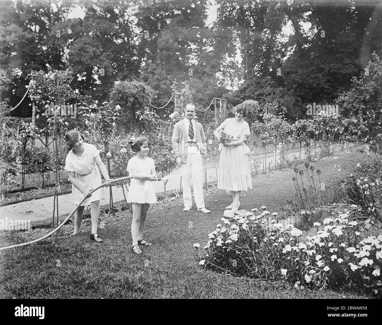 La sig.ra Zena dare (la sig.ra Maurice Brett) a casa propria. Gli Hon Maurice Brett e la signora Brett osservano le loro figlie Angela e Marie Louise che manipolano il tubo flessibile nella loro bella casa a Chileton, Windsor Forest . 27 luglio 1922 Foto Stock