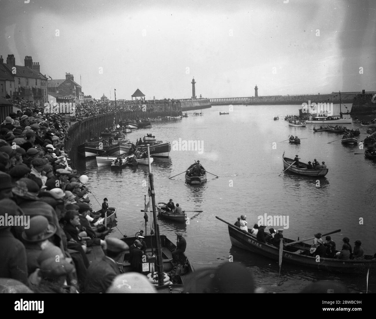 Le folle al porto di Whitby guardando le barche a remi sul fiume Esk , Yorkshire . Foto Stock