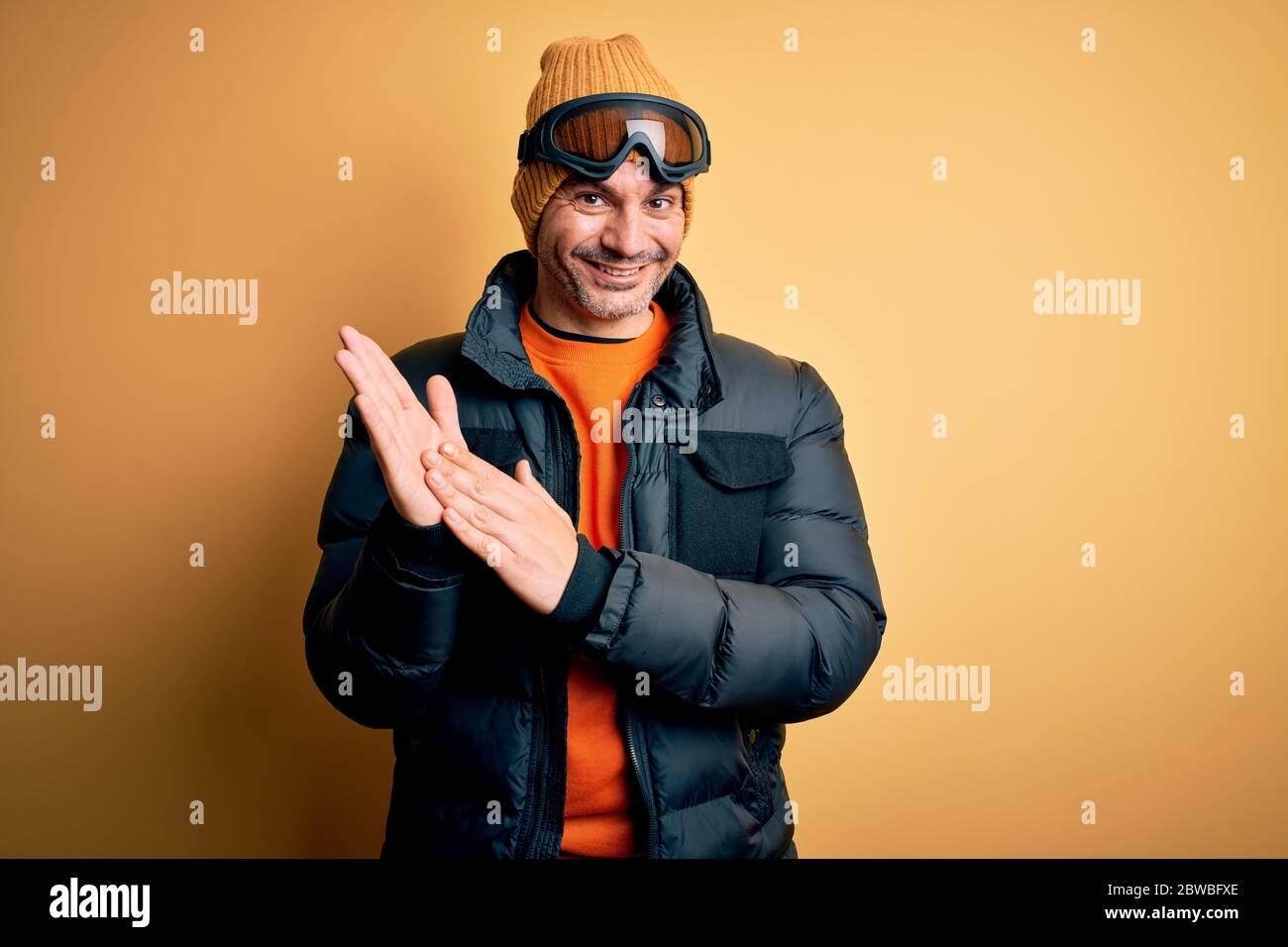 Giovane bell'uomo sciatore che indossa gli abiti da neve con occhiali da  sci che si aggrappano e applaudendo felici e gioiosi, sorridendo insieme  mani orgogliose Foto stock - Alamy