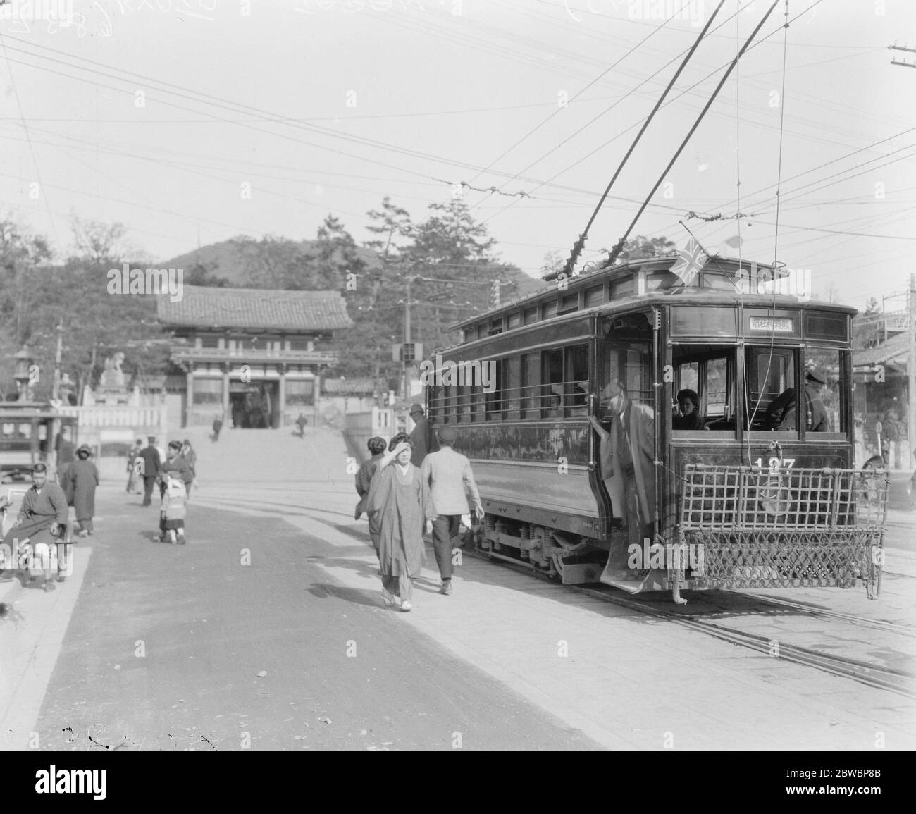 Kyoto isola di Honshu, Giappone un tram elettrico in primo piano , con una vecchia porta di accesso a uno dei molti antichi templi 3 maggio 1922 Foto Stock