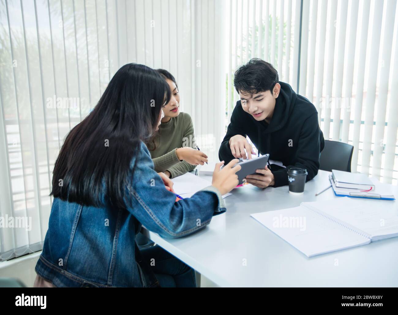 Gli studenti asiatici leggono libri e utilizzano tablet digitali per trovare informazioni per il lavoro e studi online Foto Stock