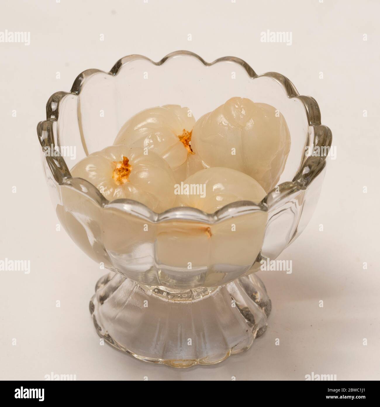 Vista ravvicinata della lychee matura in una ciotola di vetro su sfondo bianco. Foto Stock