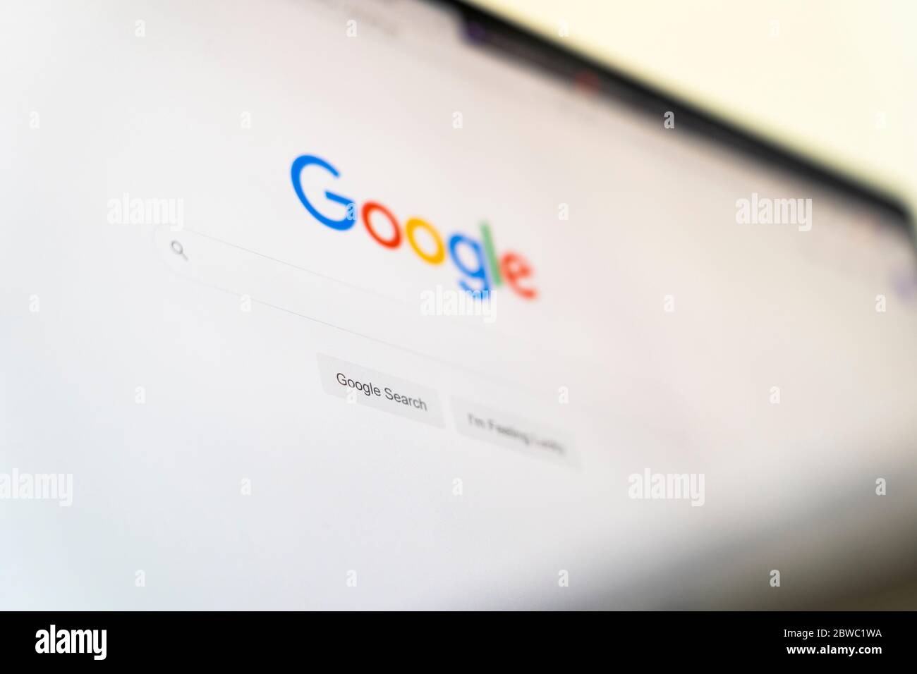 Il sito web della homepage di Google con il logo Google, la barra di ricerca e mi sento fortunato pulsante in lingua inglese su uno schermo del computer Foto Stock