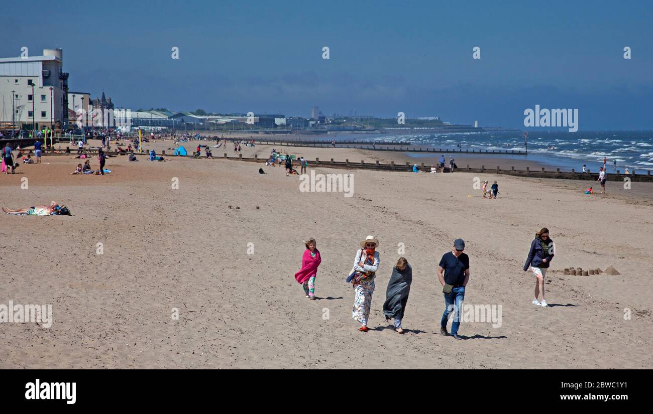 Portobello, Edimburgo, Scozia, Regno Unito. 31 maggio 2020. Soleggiato ma ventoso con 14 gradi centigradi, e ENE a 20 km/h e raffiche di 38 km/h, molti preferivano rimanere avvolti ma quelli che si stendono e seduti sulla spiaggia sembrava sentire che era abbastanza caldo tra le 12 e le 13.00. I due ufficiali di polizia sul lungomare potrebbero riferire se stessi per non mantenere la loro disanza sociale l'uno dall'altro. Una famiglia locale e tre ragazzi si sono sfidati per un po' di divertimento in mare. Credit: Arch White/Alamy Live News. Foto Stock