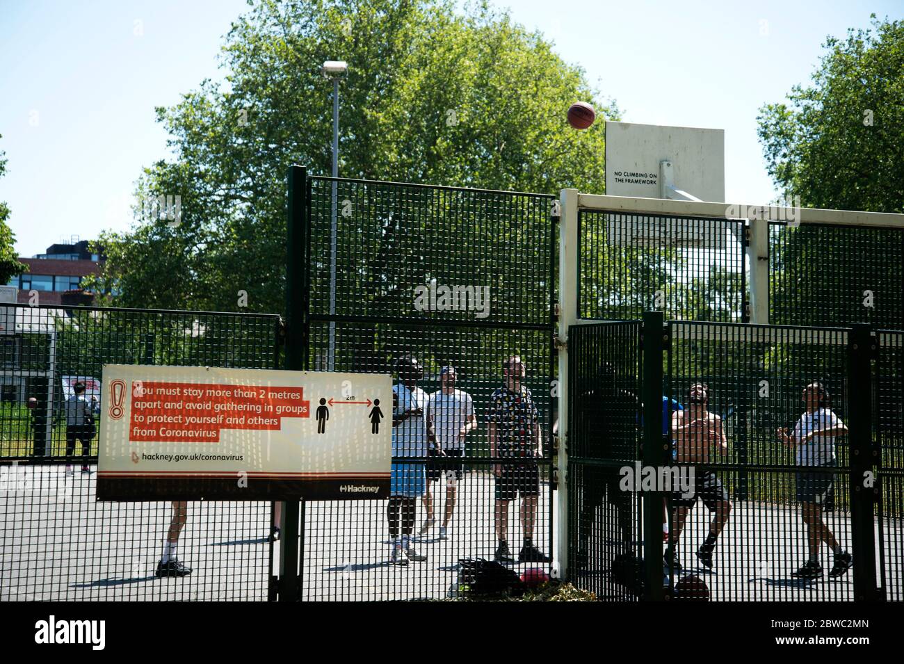 Hackney, Londra, maggio 2020 durante la pandemia di Covid-19 (Coronavirus). Un gruppo di giovani uomini gioca a basket ignorando le regole di allontanamento sociale. Foto Stock