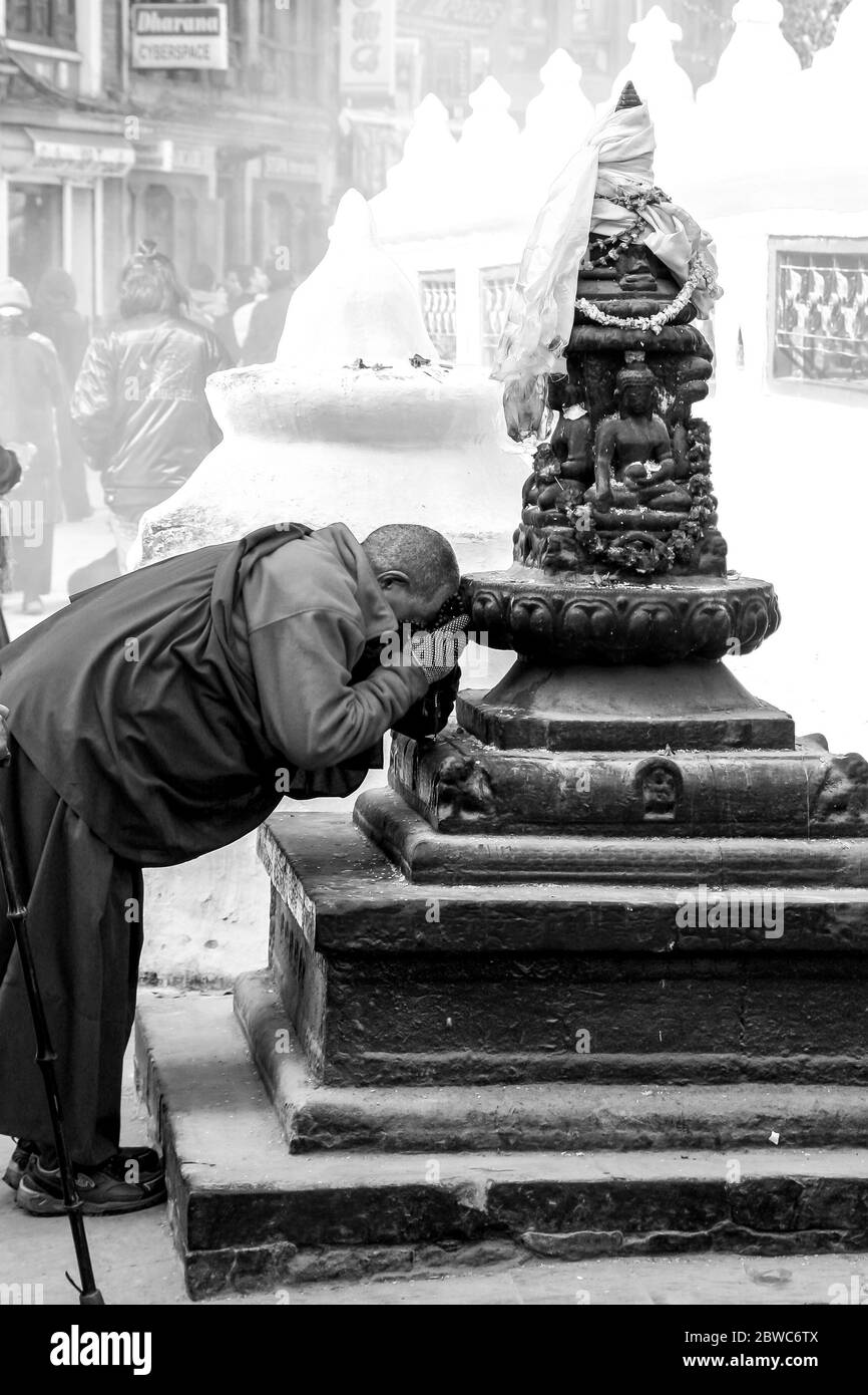 Antico monaco che prega ad una statua di Boudnath Foto Stock