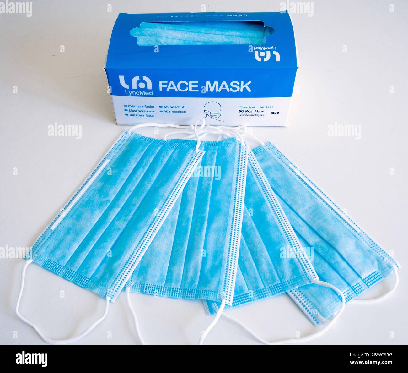 Una scatola di cinquanta maschere di copertura e quattro maschere sparse realizzate dalla compagnia italiana Lyncmed su richiesta durante la pandemia di Coronavirus su una schiena bianca Foto Stock