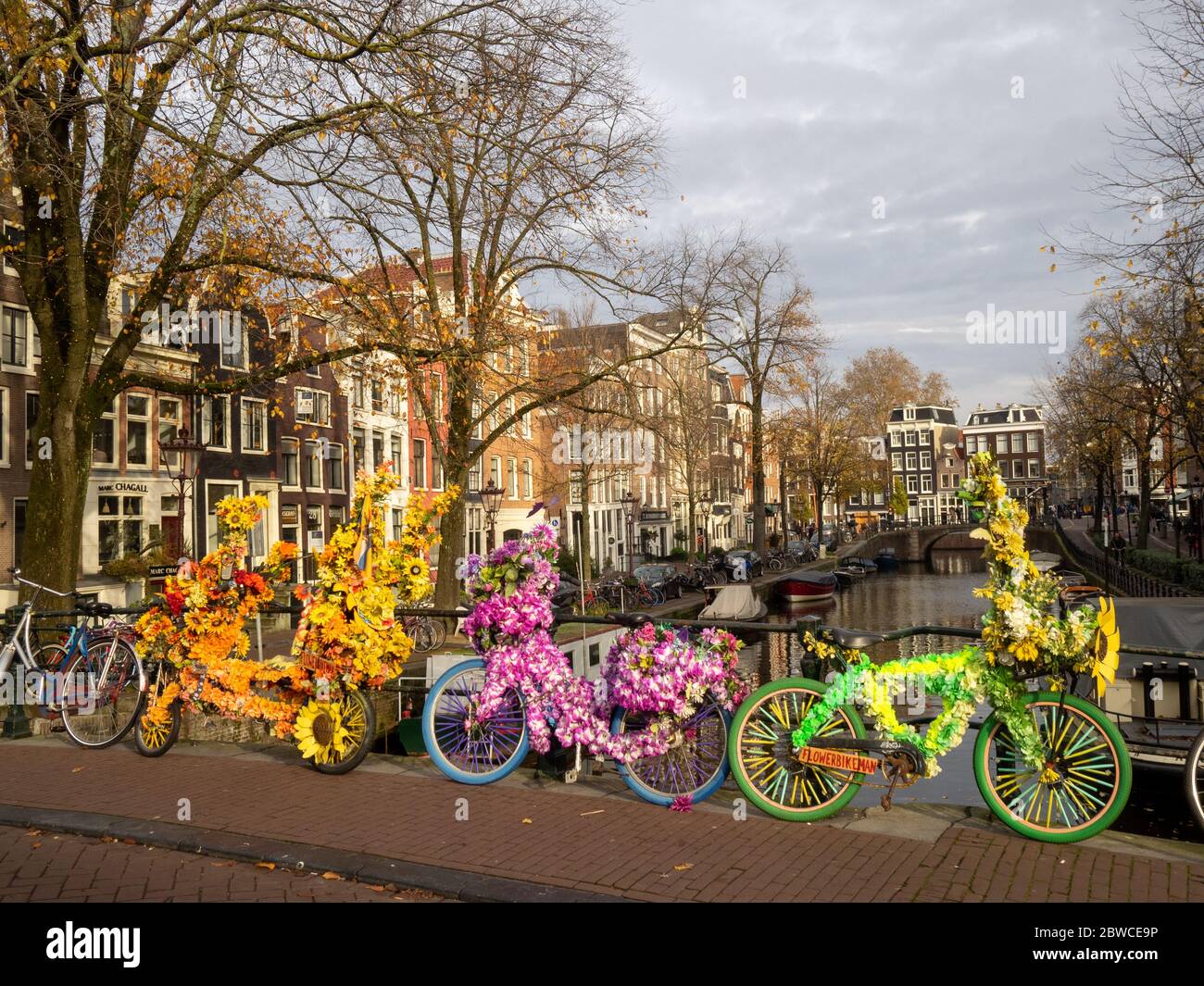 Biciclette colorate parcheggiate in un ponte su un canale in Amsterdam Foto Stock